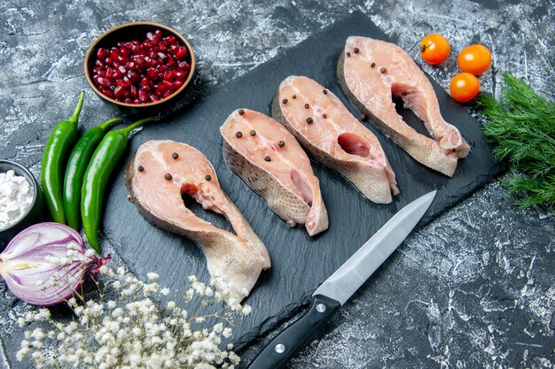 Ansicht von unten rohe Fischscheiben auf Tafelmesser Gemüse kleine weiße Blumen auf Grau