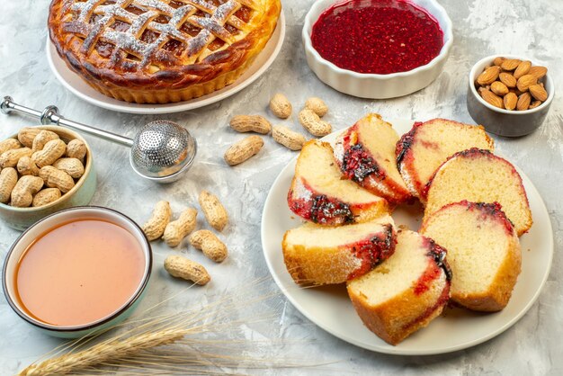 Ansicht von unten Scheiben von Marmeladenkuchen und Torte mit Marmelade auf Tellern, anderen Stoffen in Schalen auf dem Tisch