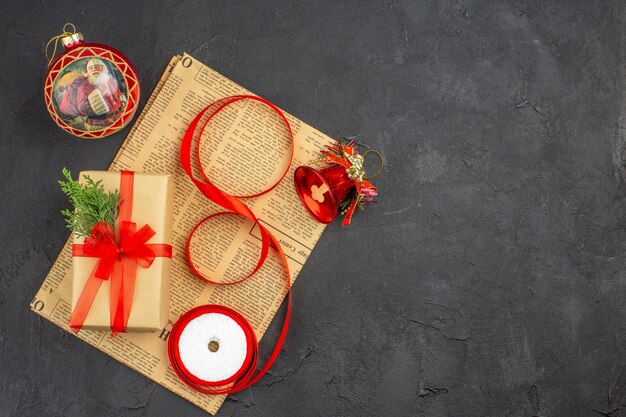 Ansicht von unten Weihnachtsgeschenk in braunem Papier Zweig Tannenband auf Zeitungsweihnachtsschmuck auf dunklem Hintergrund Kopie Raum