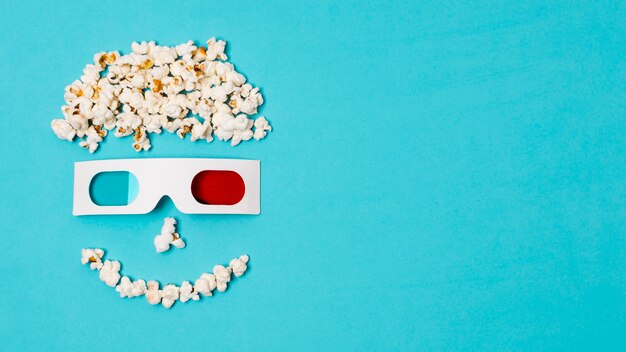 Anthropomorphes Gesicht des smiley gemacht mit Popcorn und Gläsern 3d über dem Kinozeittext