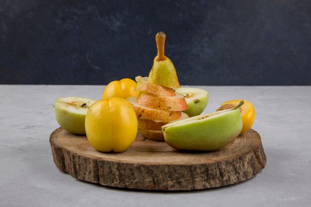 Apfel, Birne und Pfirsiche auf einem Stück Holz auf Blau