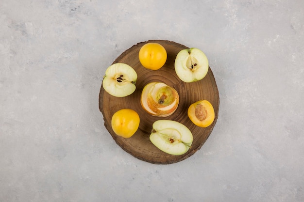Apfel, Birne und Pfirsiche auf einem Stück Holz in der Mitte