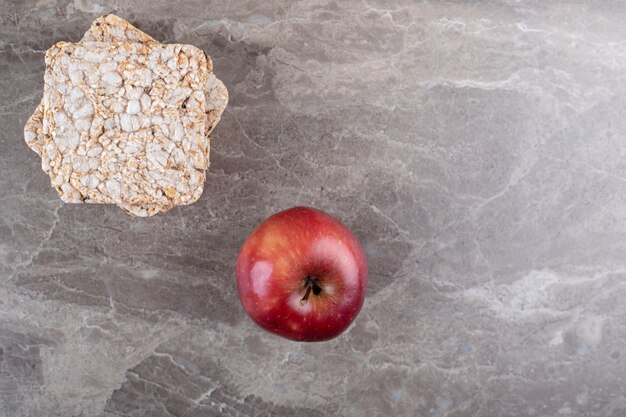 Apfel und ein Haufen Puffreiskuchen auf der Marmoroberfläche