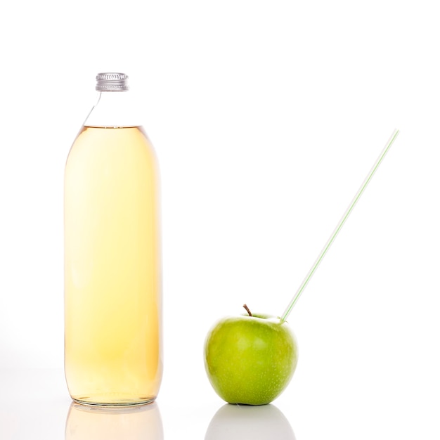 Apfelsaft in einer Glasflasche und grüner Apfel mit Strohhalm