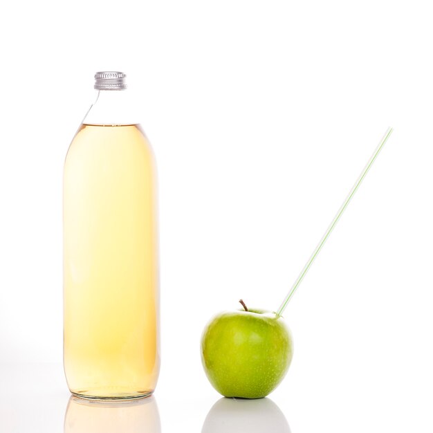 Apfelsaft in einer Glasflasche und grüner Apfel mit Strohhalm