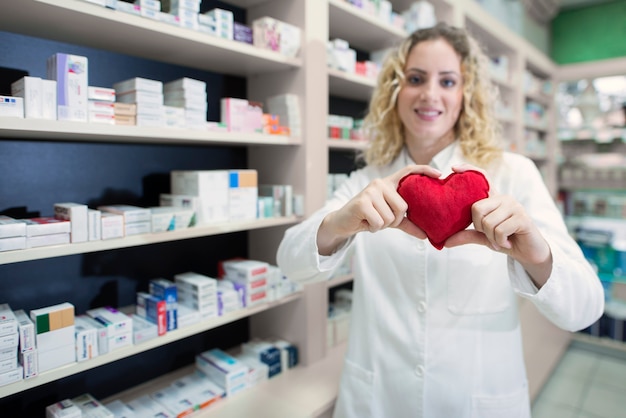 Apothekerin, die Herz hält und Herz-Kreislauf-Medikamente und erfolgreiche Behandlung fördert