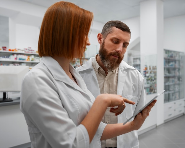 Apothekerin schult männlichen Kollegen mit Tablet in der Apotheke