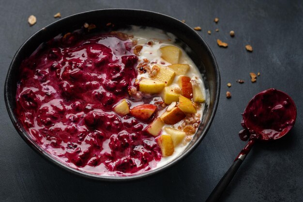 Appetitanregendes hausgemachtes Müsli mit Beeren und Joghurt in Schüssel auf dunklem Hintergrund serviert.