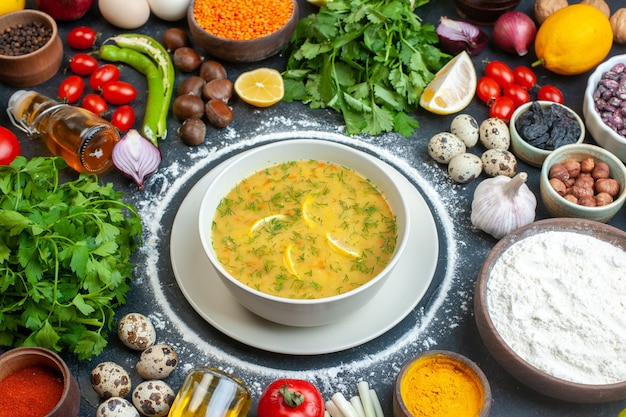 Appetitliche Suppe serviert mit Zitrone und Grün in einer weißen Schüssel und Mehl Tomatenöl Flasche Mehl Grün bündelt Eier auf dunklem