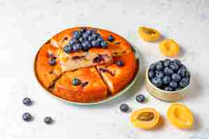 Kostenloses Foto aprikosen-heidelbeer-kuchen mit frischen blaubeeren und aprikosenfrüchten.