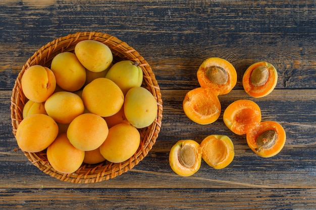 Aprikosen in einem Weidenkorb auf Holztisch, flach liegen.