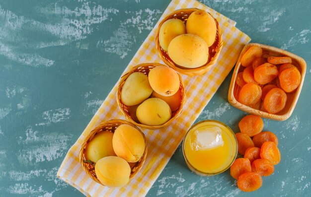 Aprikosen in Körben mit getrockneten Aprikosen, Saft flach auf Gips und Picknicktuch liegen