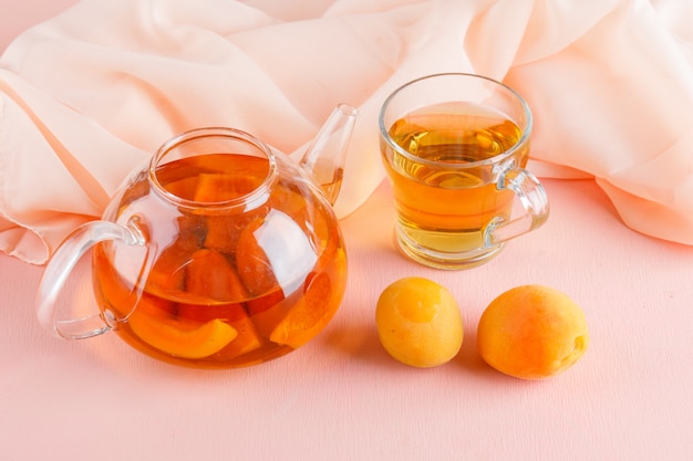 Aprikosentee mit Aprikosen in Teekanne und Becher, Draufsicht.