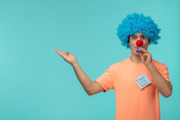 Kostenloses Foto aprilscherz-tageskerl roter nasenclown lustiger blauer pfeifenhaar blauer post-it aufkleber, der hände zeigt