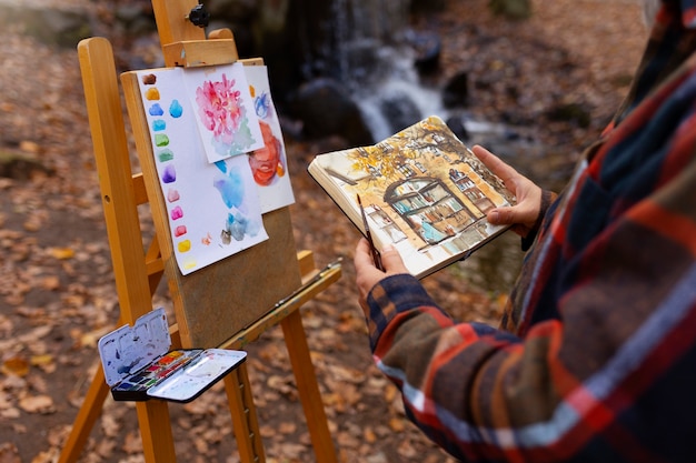 Aquarellmaler draußen im Wald mit Staffelei und Leinwand