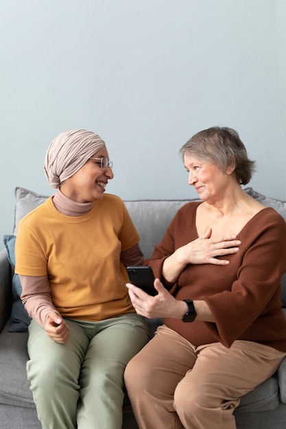Arabische Frau bringt Seniorin bei, Smartphone im Wohnzimmer zu benutzen