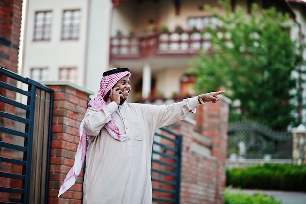 Arabischer Geschäftsmann aus dem Nahen Osten posierte auf der Straße gegen modernes Gebäude mit Handy und zeigte Finger