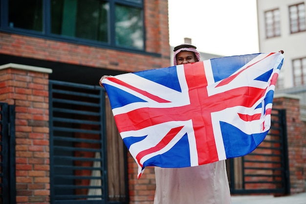 Arabischer Mann aus dem Nahen Osten posierte auf der Straße mit dem Konzept der britischen Flagge England und der arabischen Länder