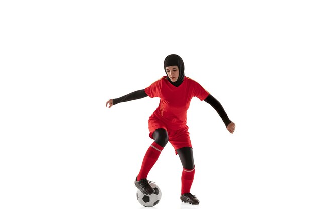 Arabischer weiblicher Fußball oder Fußballspieler lokalisiert auf weißem Studiohintergrund. Junge Frau, die den Ball tritt, trainiert, in Bewegung und Aktion übt.