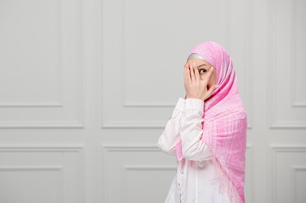 Arabisches Mädchen, eingewickelt in einen schönen rosafarbenen Hijab, hübsche süße junge muslimische Frau, die das Gesicht bedeckt