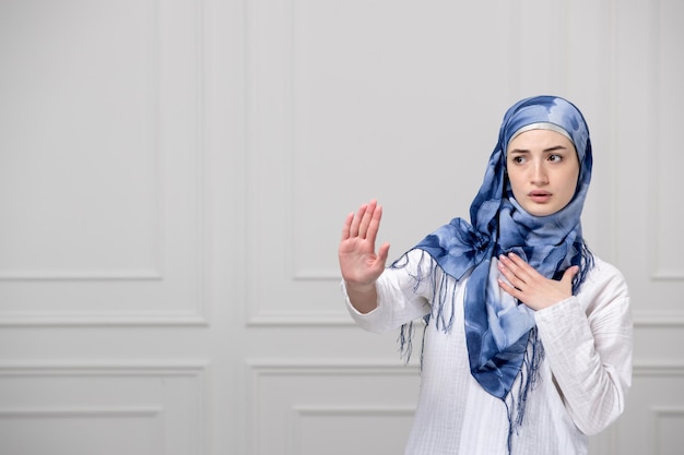 Arabisches Mädchen wickelte den Kopf in blau-weißen Hijab, schöne muslimische süße junge Dame, die jemanden aufhält