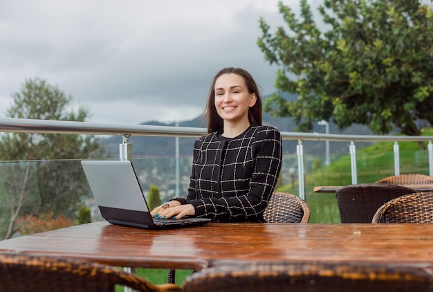 Arbeiten an Laptop-Bloggerin schaut in die Kamera auf Naturansichtshintergrund