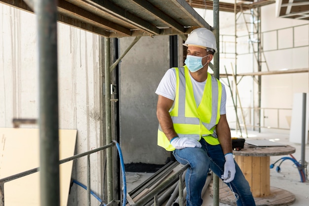 Arbeiter auf einer Baustelle, die medizinische Maske trägt