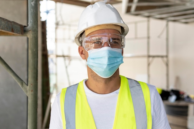 Arbeiter, der medizinische Maske auf einer Baustelle trägt