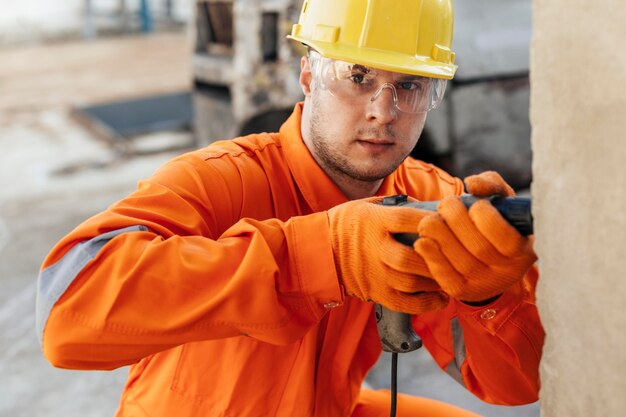 Arbeiter in Uniform mit Schutzbrille und Bohrer