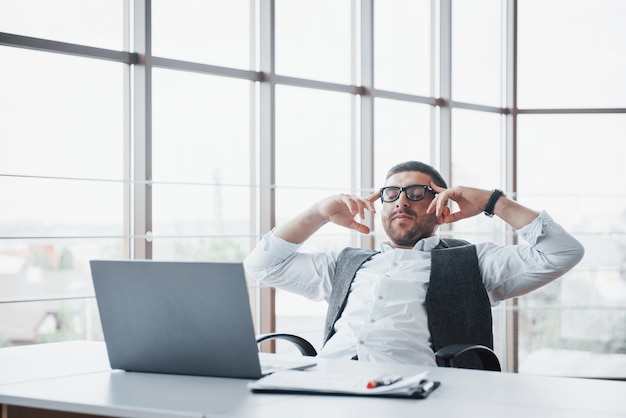 Arbeiter ist ein junger Mann mit einem Laptop im Büro