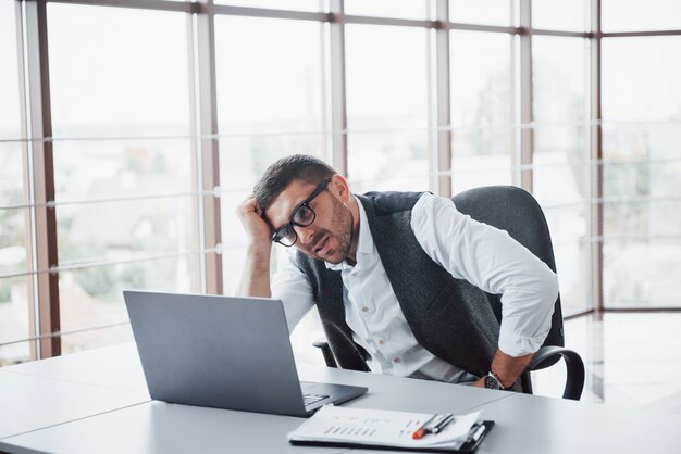 Arbeiter ist ein junger Mann mit einem Laptop im Büro