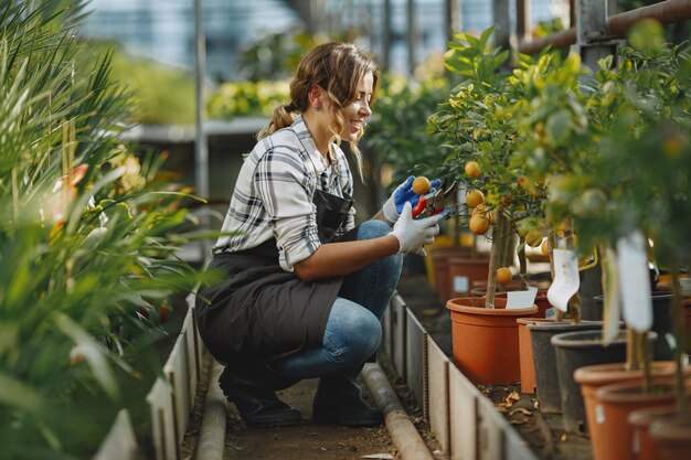 Arbeiter kümmern sich um Blumenbeete. Mädchen in einem weißen Hemd. Frau in Handschuhen