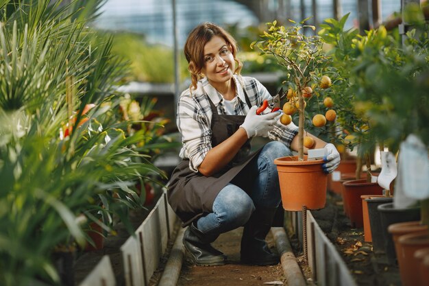 Arbeiter kümmern sich um Blumenbeete. Mädchen in einem weißen Hemd. Frau in Handschuhen