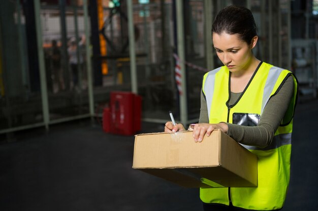 Arbeiterin, die auf Kasten im Lager schreibt