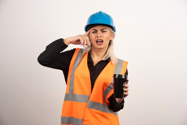 Arbeiterin mit Tasse Tee, der Kopfschmerzen hat. Hochwertiges Foto