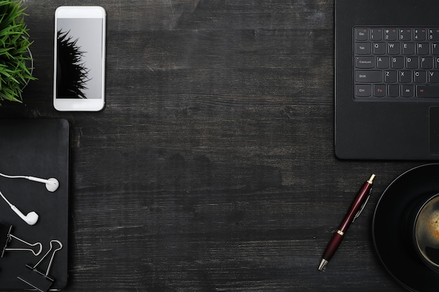 Arbeitsplatz mit Smartphone, Laptop, auf schwarzem Tisch. Copyspace-Hintergrund der Draufsicht