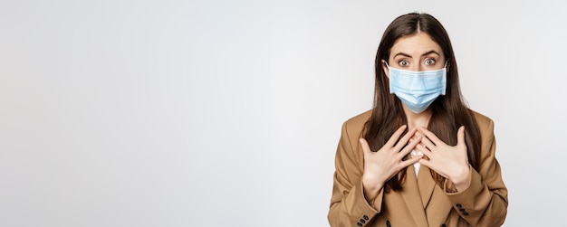 Kostenloses Foto arbeitsplatz- und pandemiekonzept schockierte geschäftsfrau im gesicht mit medizinischer maske, die erschrocken nach luft schnappte