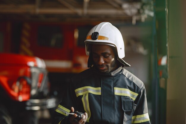 Arfican Feuerwehrmann in Uniform. Mann bereitet sich auf die Arbeit vor. Guy benutzt einen Funksender.
