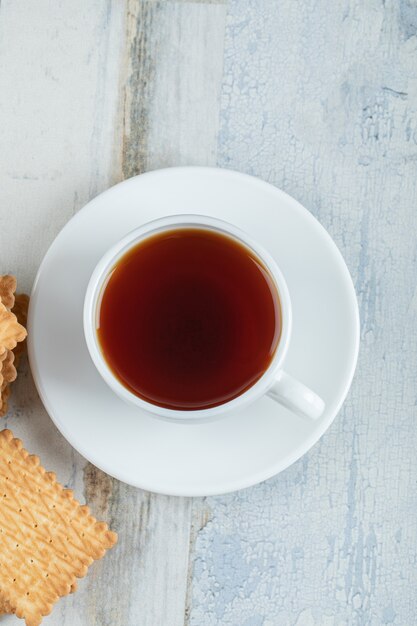 Aromatasse Tee mit leckeren Crackern auf einem Holztisch.