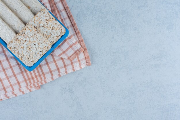 Aromatisch geschnittene Sonnenblumenhalva und Puffreiskuchen in Tablett auf Handtuch.