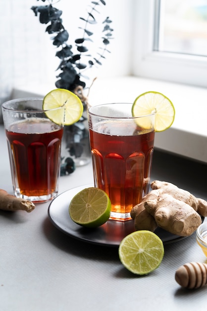 Arrangement mit einem Glas Tee und Limette