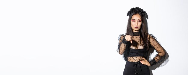 Arrogante und freche asiatische böse Hexenfrau im Halloween-Kostüm, die mit dem Finger auf dich zeigt und mich anschaut