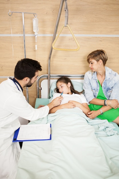 Arzt, der die Körpertemperatur ihres Patienten im Krankenhauszimmer misst