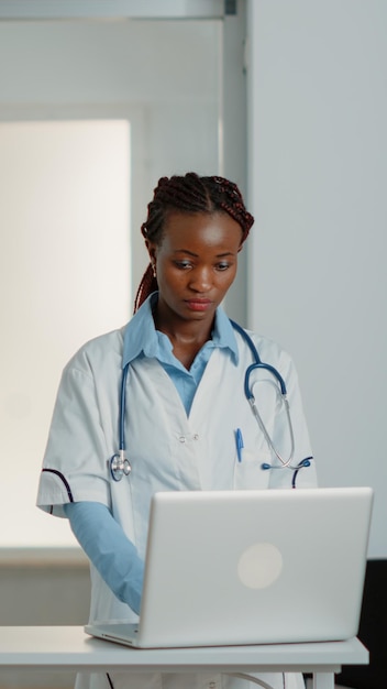 Arzt, der mit Technologie auf einem modernen Laptop in der Krankenstation arbeitet. Medizinischer Spezialist, der ein Gerät verwendet, um am Gesundheitssystem zu arbeiten und kranken Patienten bei der Behandlung und Medizin hilft.