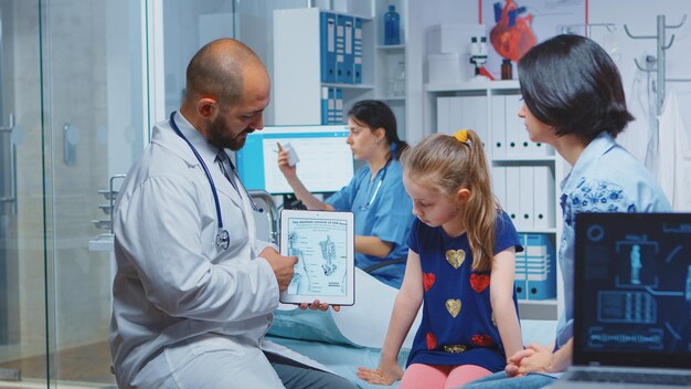 Arzt, der während der Konsultation Skelettgrafiken auf dem Tablet zeigt. Heilpraktiker Arzt Facharzt für Medizin, der Gesundheitsdienste Röntgenuntersuchung im Krankenhaus anbietet