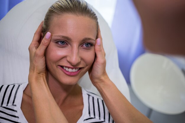 Arzt, der weibliches Patientengesicht in der Klinik untersucht