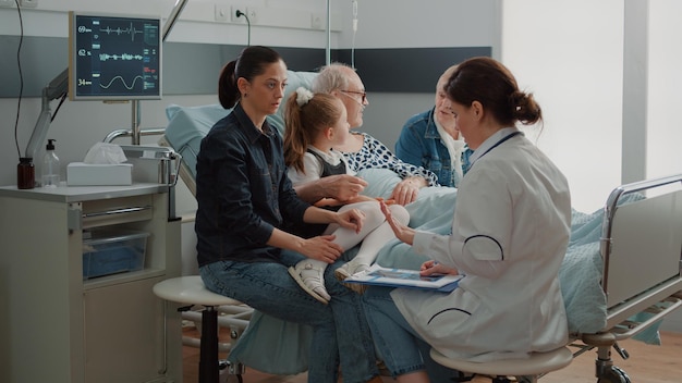 Arzt erklärt der Tochter eines kranken Patienten auf der Krankenstation den Röntgenscan. Ärztin, die der Mutter des kleinen Mädchens die Ergebnisse der Röntgendiagnose zeigt und über Behandlung und Genesung spricht.