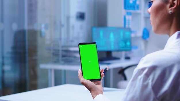 Arzt hält Smartphone mit Kopienraum im Klinikschrank und Krankenschwester öffnende Glastür. Gesundheitsspezialist im Krankenhausschrank mit Smartphone mit Modell.