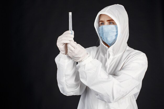 Arzt in einer medizinischen Maske. Coronavirus-Thema. Über schwarzer Wand isoliert. Frau im Schutzanzug.