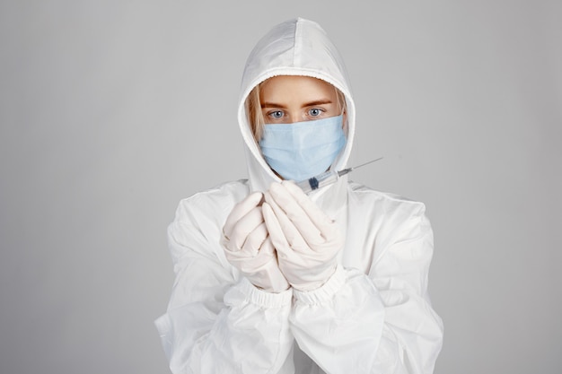 Arzt in einer medizinischen Maske. Coronavirus-Thema. Über weißer Wand isoliert. Frau im Schutzanzug.